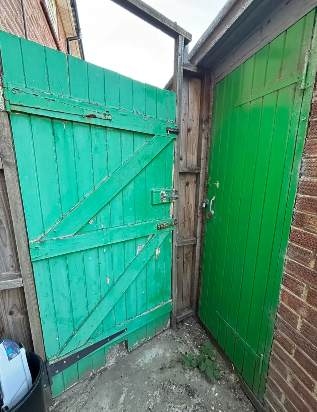 Old side gate with rotten, broken timber at the base